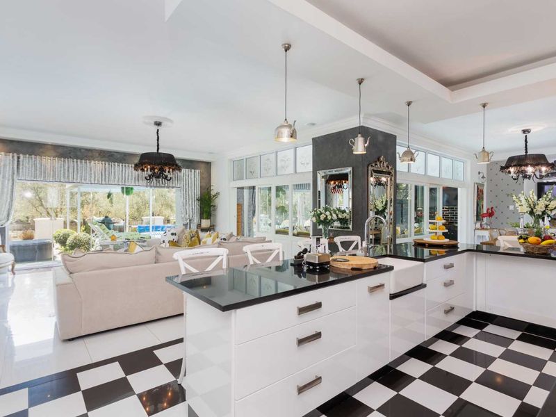 Spacious open-plan kitchen and living area featuring a large island with granite countertops, farmhouse sink, and distinctive checkerboard flooring with seamless outdoor access.