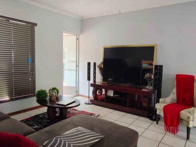 A living room featuring tiled flooring, venetian blinds, and a sliding door leading to an outdoor area.