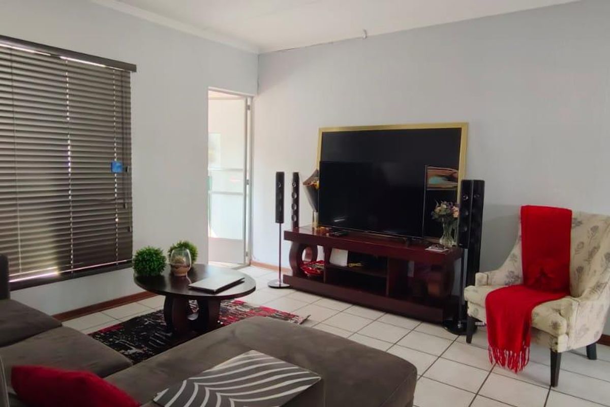 A living room featuring tiled flooring, venetian blinds, and a sliding door leading to an outdoor area.