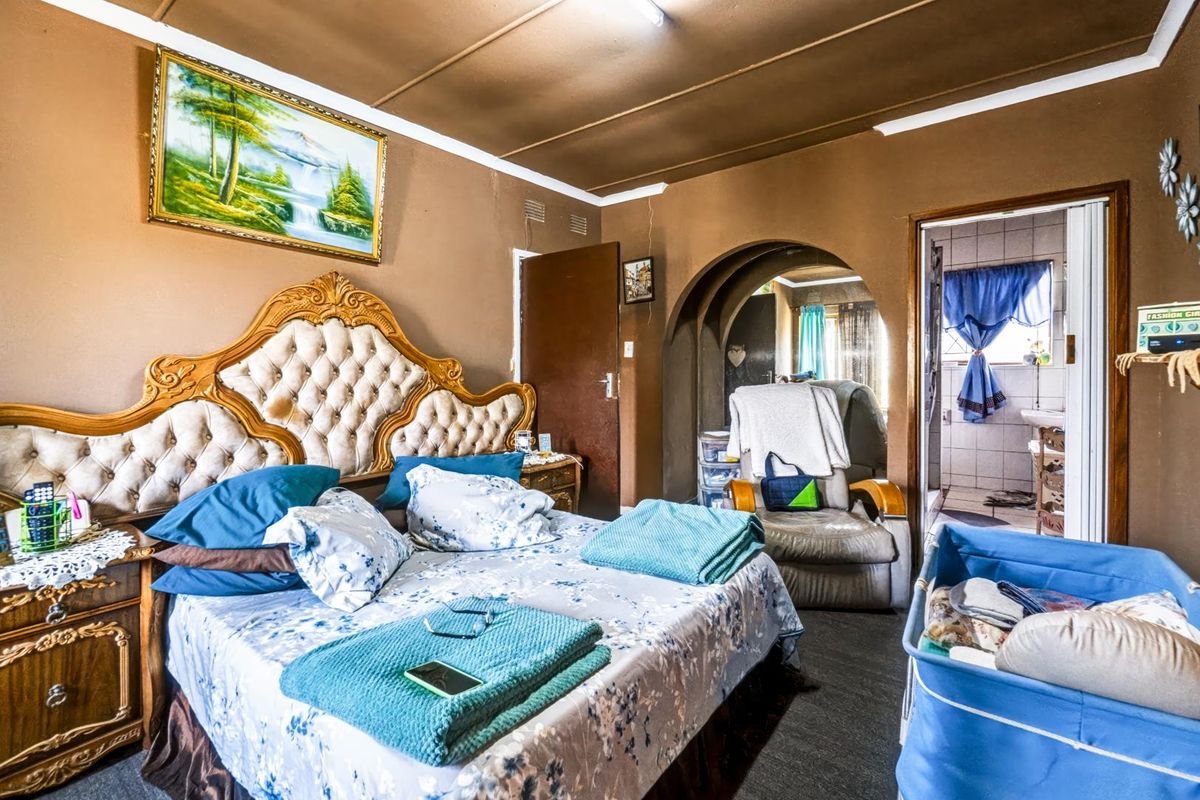 A bedroom featuring an arched doorway leading to an en-suite bathroom, with tiled flooring and neutral wall tones.