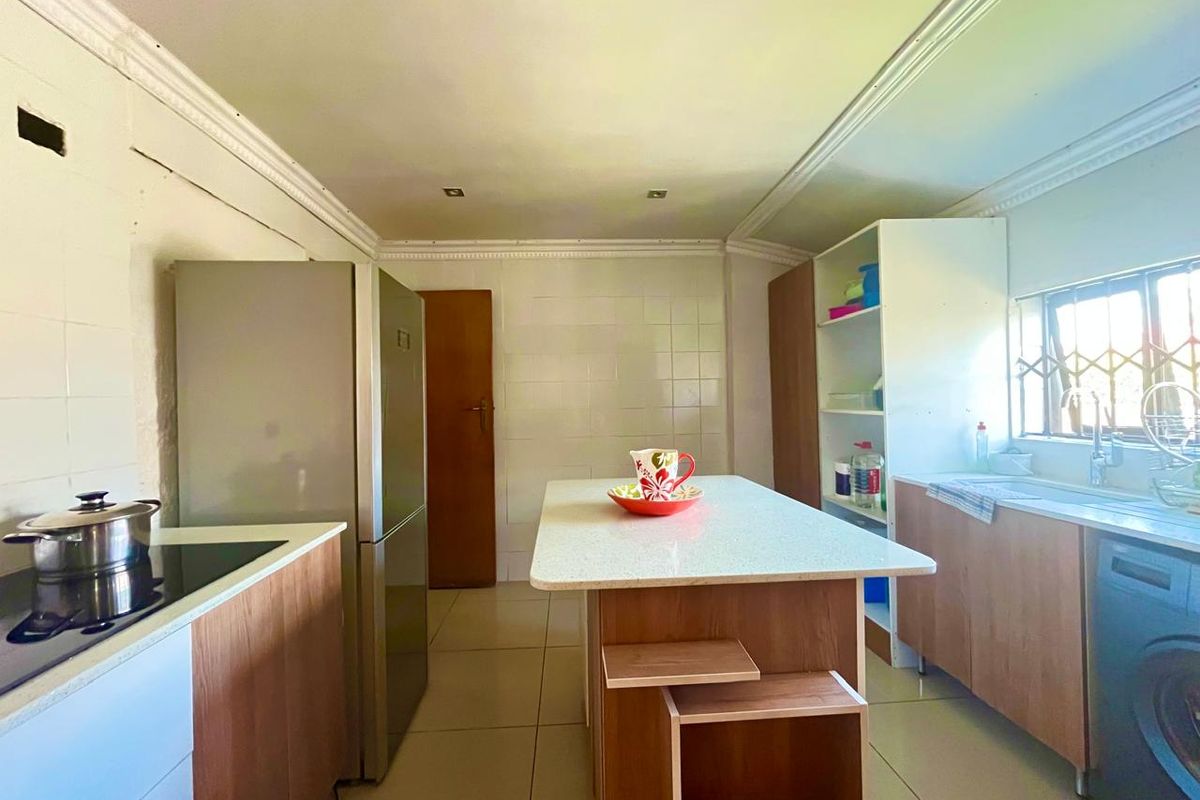 A functional kitchen featuring a central island, tiled backsplash, and built-in cabinetry, offering a practical layout with potential for cosmetic updates.