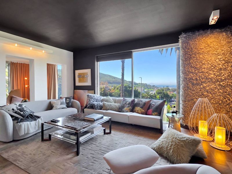 A modern living room featuring a large picture window with scenic views, a dark ceiling, and a unique textured feature wall.