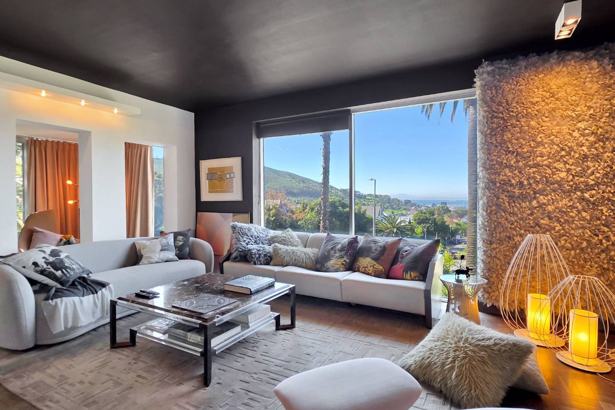 A modern living room featuring a large picture window with scenic views, a dark ceiling, and a unique textured feature wall.