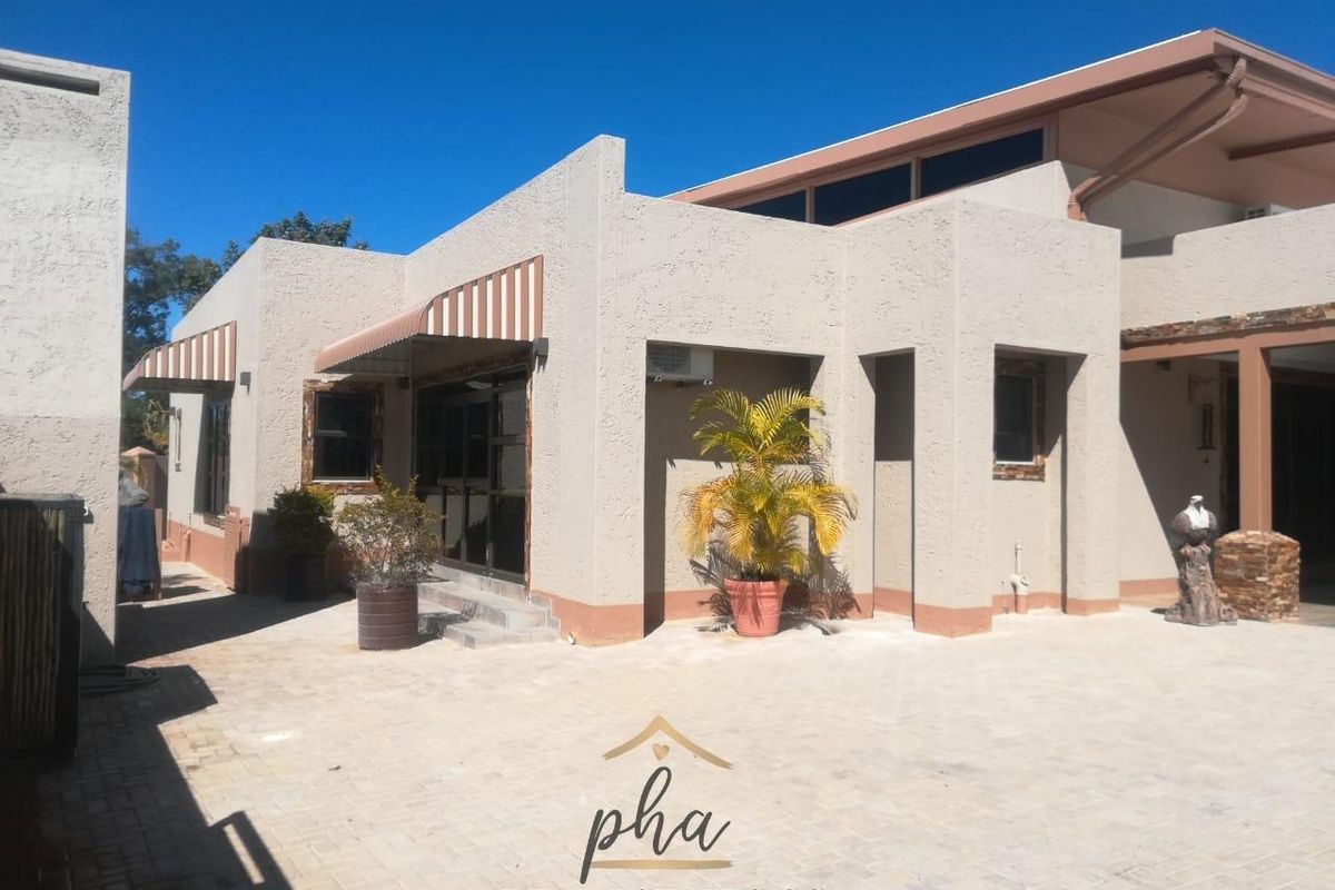 Rear exterior view of the property featuring a paved courtyard, stucco facade, and covered patio area with sliding glass doors.