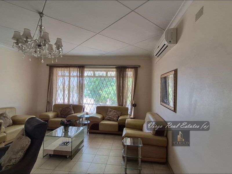 Spacious living room featuring tiled flooring, a split-system air conditioner, and a decorative chandelier, providing a comfortable and functional family space.