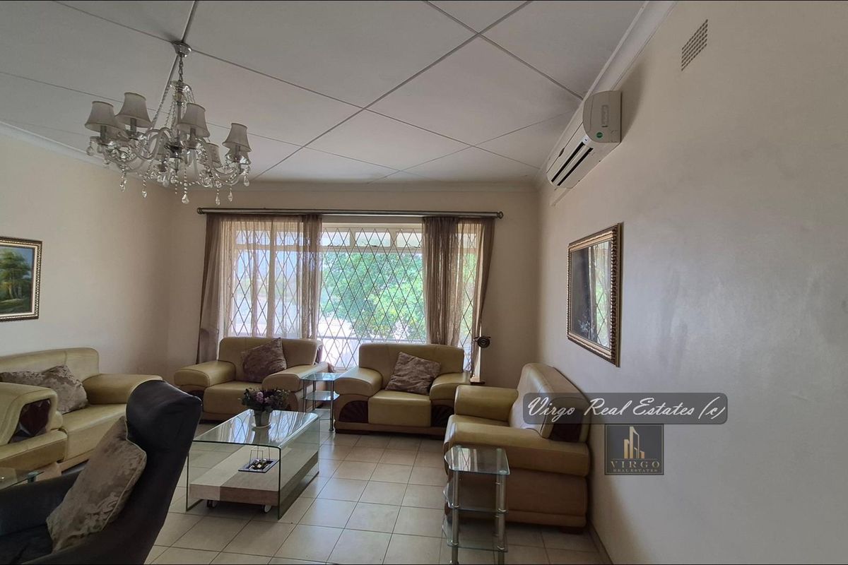 Spacious living room featuring tiled flooring, a split-system air conditioner, and a decorative chandelier, providing a comfortable and functional family space.