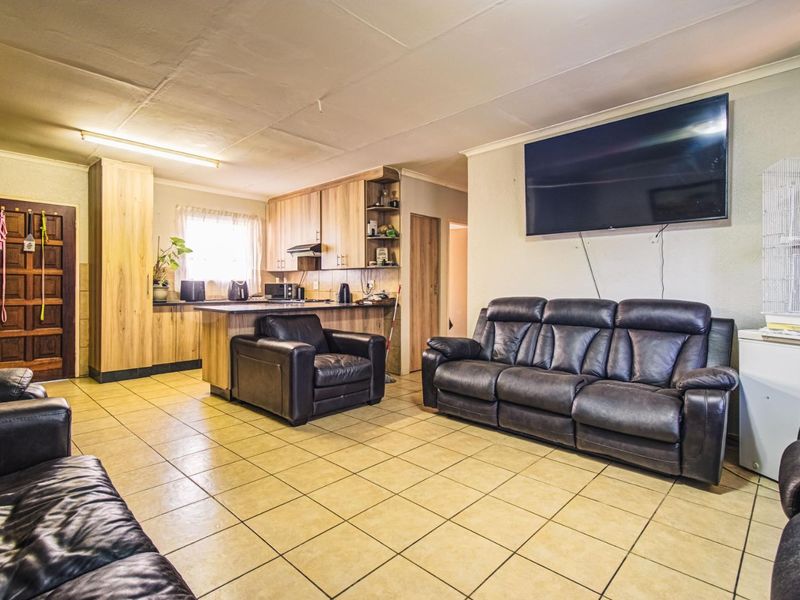 Open-plan living and kitchen area featuring tiled flooring, built-in cabinetry, and a functional layout suitable for modern updates.