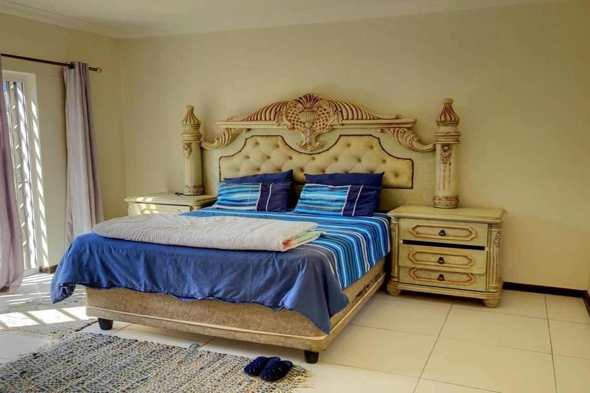 A spacious bedroom featuring light-colored floor tiles and a sliding glass door providing natural light.