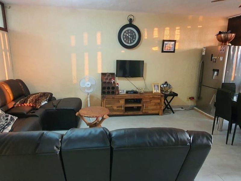 An open-plan living and dining area featuring tiled flooring and a ceiling fan, providing a functional space for relaxation and meals.