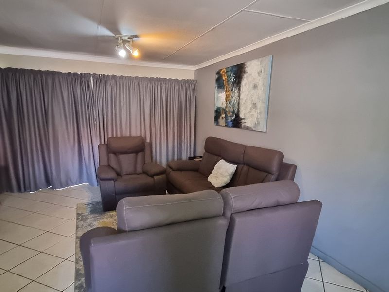 A comfortable living room featuring tiled flooring, neutral wall tones, and ceiling cornice detailing, providing a functional space for relaxation.