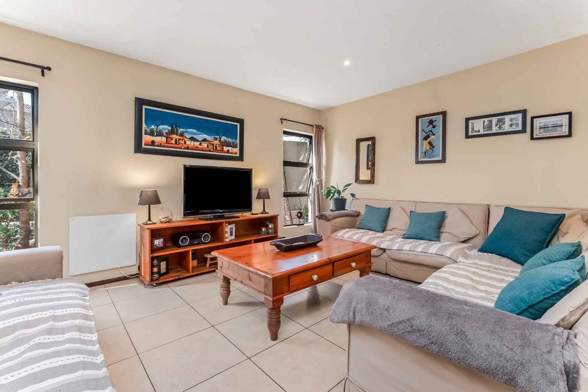 A comfortable living room featuring tiled flooring, neutral wall tones, and large windows that provide natural light.