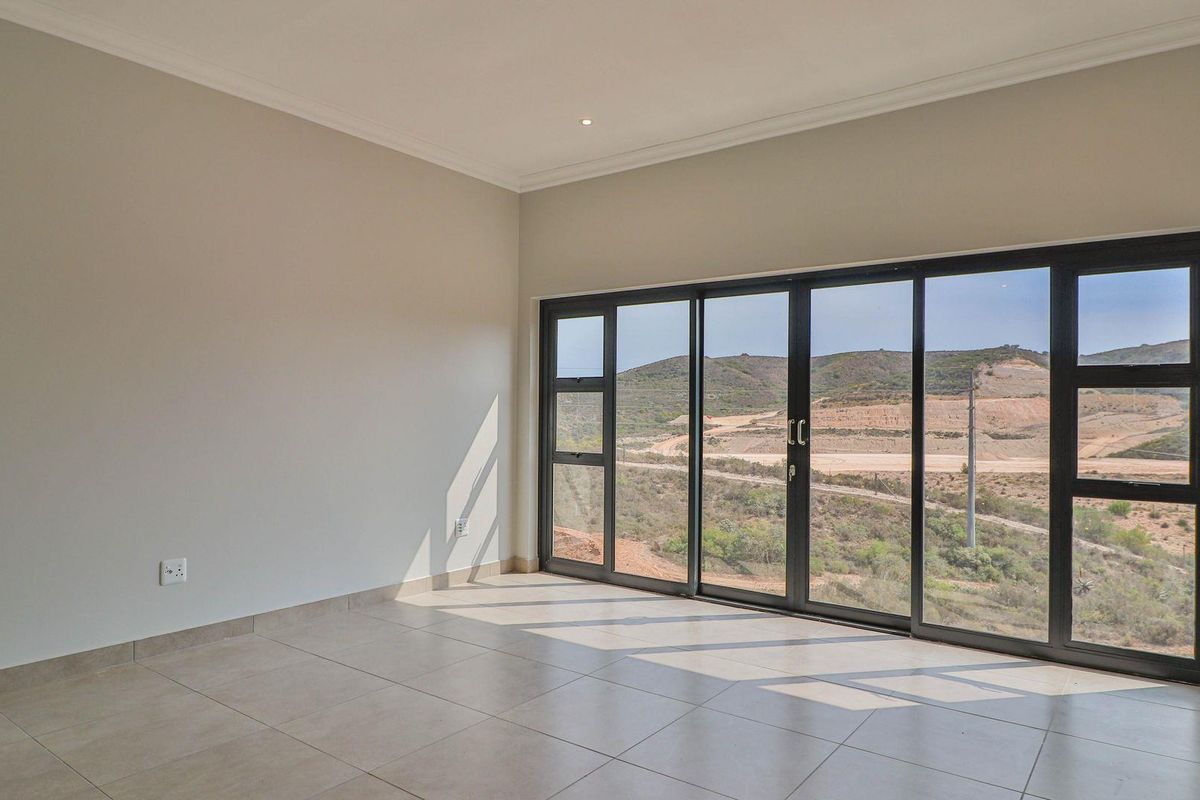 A bright, empty living area featuring large black-framed sliding glass doors that offer expansive views of the surrounding landscape.