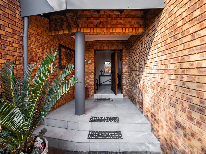 A welcoming entrance featuring face brick walls, tiled steps, and a covered porch area leading into the home.