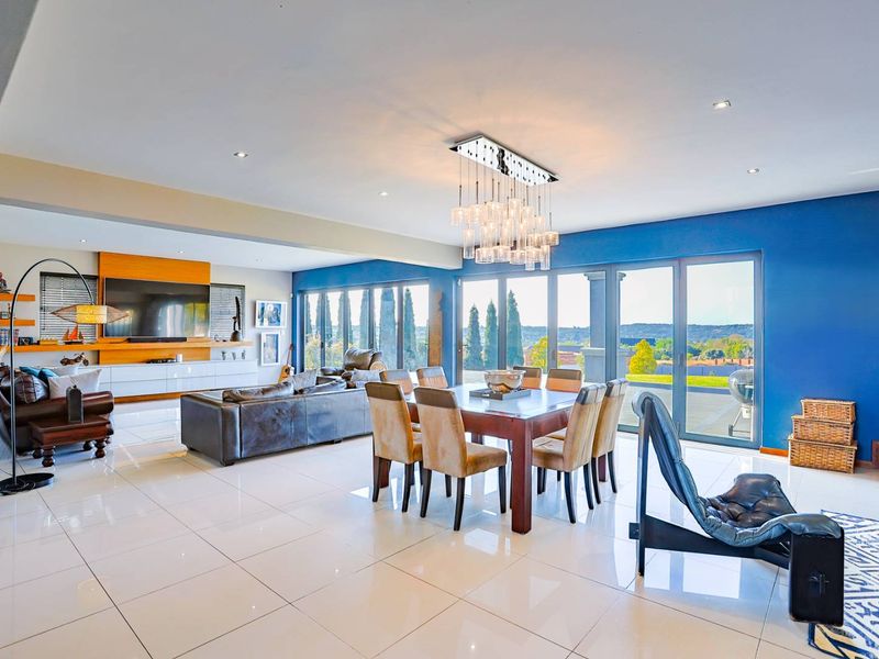 Spacious open-plan living and dining area featuring large format floor tiles, modern recessed lighting, and expansive stacking doors leading to the outdoor space.