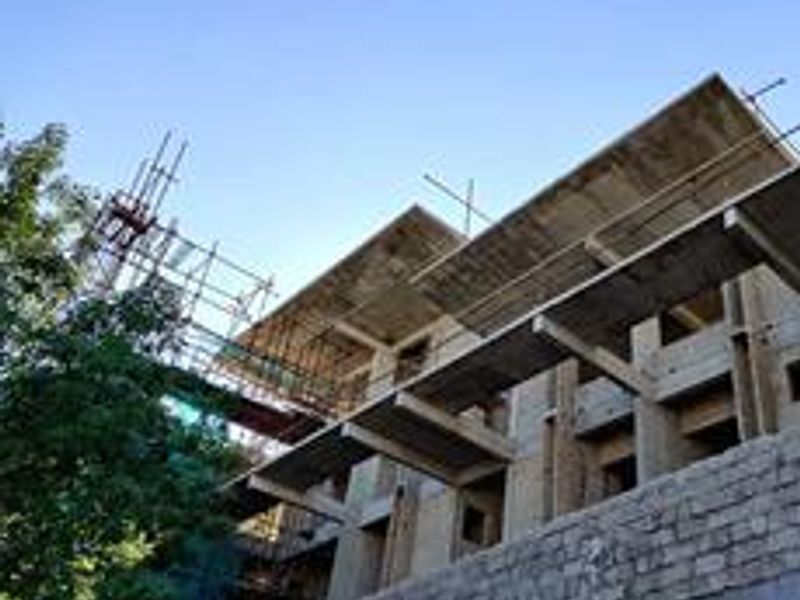 Exterior view of a multi-story office building currently under construction, featuring exposed concrete structural elements and scaffolding.