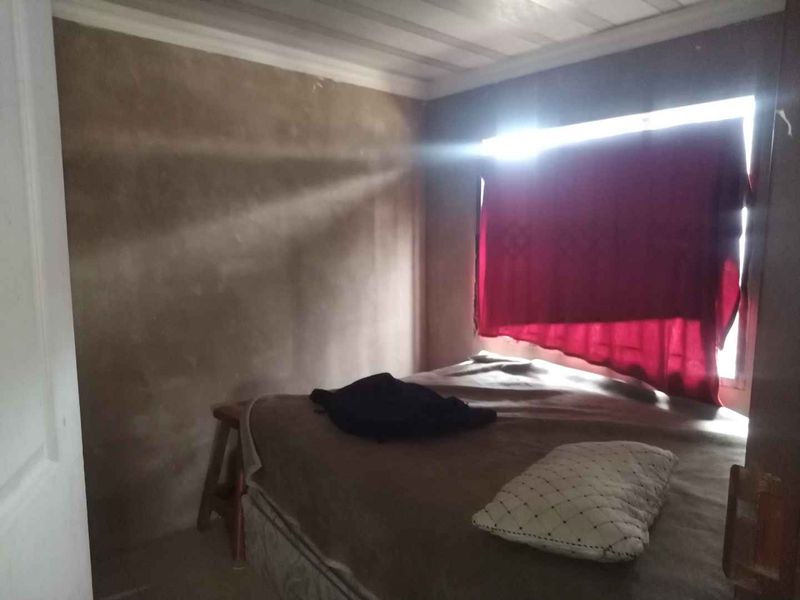 A bedroom featuring a timber ceiling and unfinished wall surfaces, requiring cosmetic updates to improve the overall finish and aesthetic appeal.