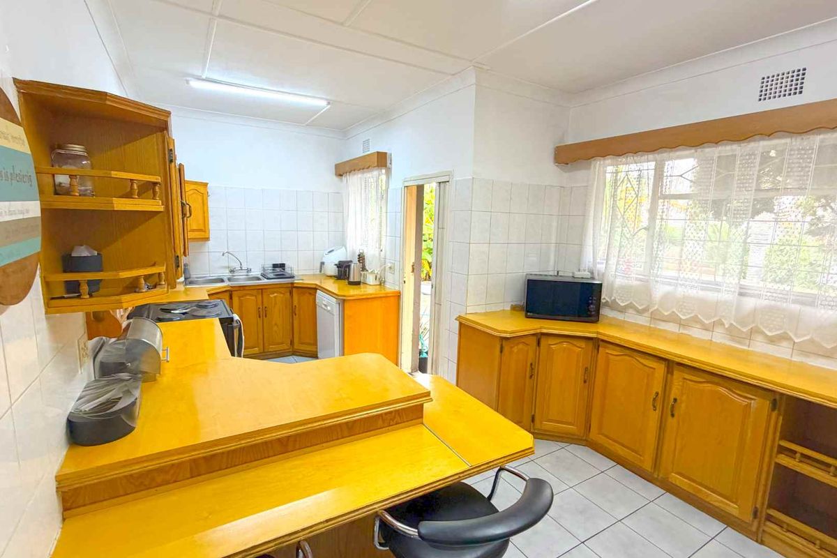 A functional kitchen featuring wooden cabinetry, tiled splashbacks, and a breakfast bar, offering a traditional layout with ample storage and workspace.