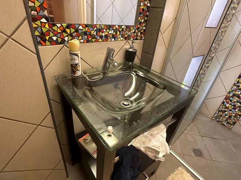Bathroom featuring a glass vessel sink vanity, mosaic tile accents, and a tiled shower enclosure with a floor drain.