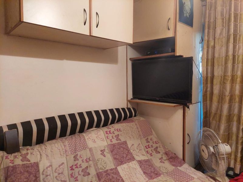 A compact bedroom featuring built-in overhead cabinetry and storage units, providing functional space-saving solutions within the room.