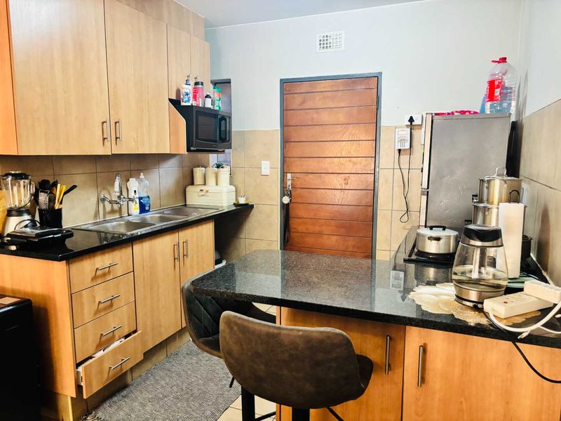 A functional kitchen featuring wooden cabinetry, granite countertops, a double sink, and a built-in breakfast nook with tiled backsplash.