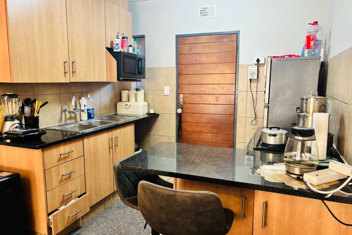 A functional kitchen featuring wooden cabinetry, granite countertops, a double sink, and a built-in breakfast nook with tiled backsplash.