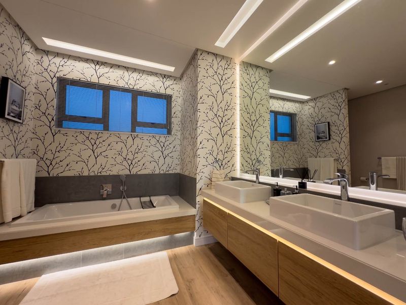 Modern, well-appointed bathroom featuring a double vanity with vessel sinks, integrated under-cabinet lighting, and a spacious built-in bathtub with contemporary finishes.