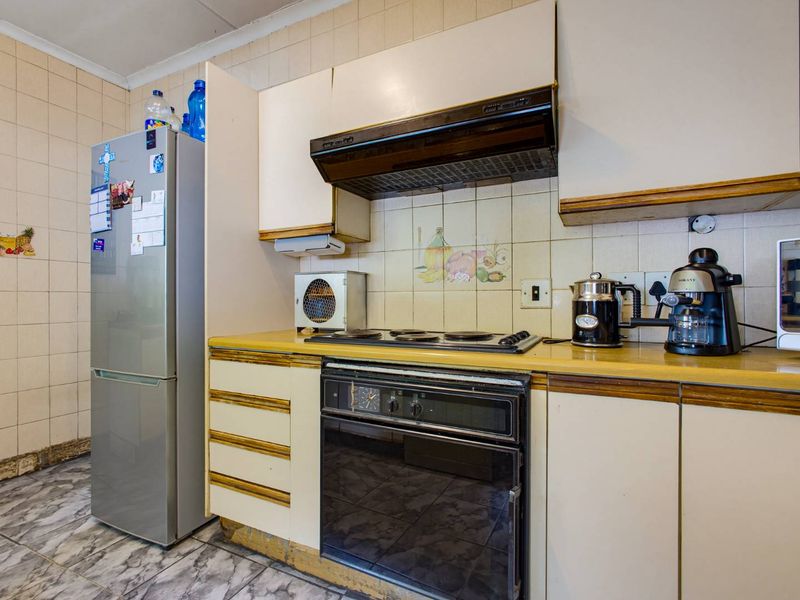 A functional kitchen featuring built-in cabinetry, an integrated oven and hob, and tiled splashbacks, offering potential for a modern renovation.