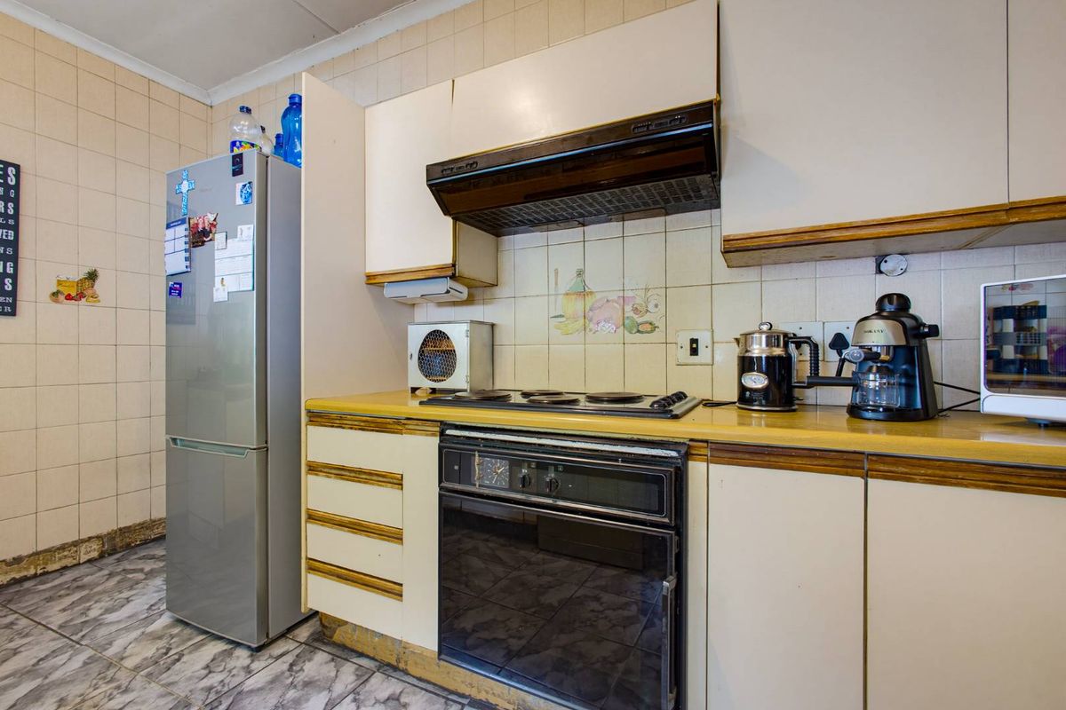 A functional kitchen featuring built-in cabinetry, an integrated oven and hob, and tiled splashbacks, offering potential for a modern renovation.