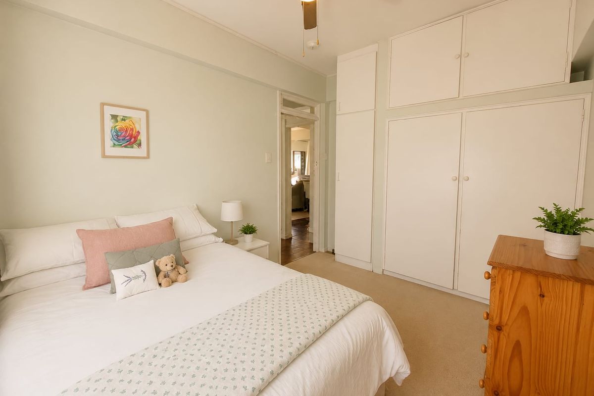 A well-maintained bedroom featuring built-in storage cupboards, a ceiling fan, and neutral carpeting, offering a comfortable and functional living space.