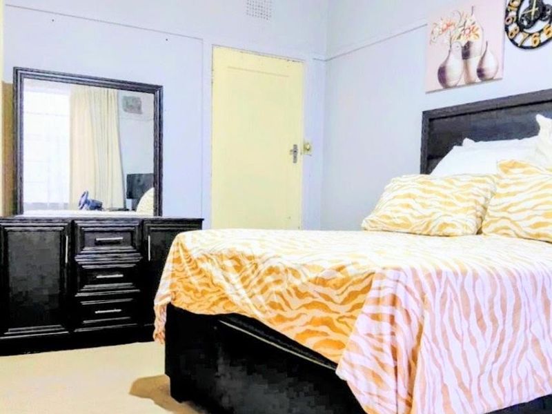 A bedroom featuring neutral wall finishes, a standard interior door, and a ventilation grille, providing a functional space for rest.