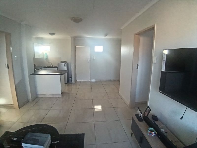 Open plan living area featuring tiled flooring and a functional kitchen space with built-in cabinetry and countertops.