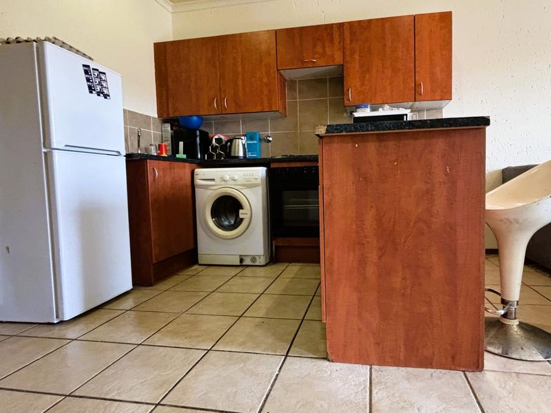 Compact kitchen featuring wood-look laminate cabinetry, tiled backsplash, and built-in oven, offering a functional layout with tiled flooring throughout.