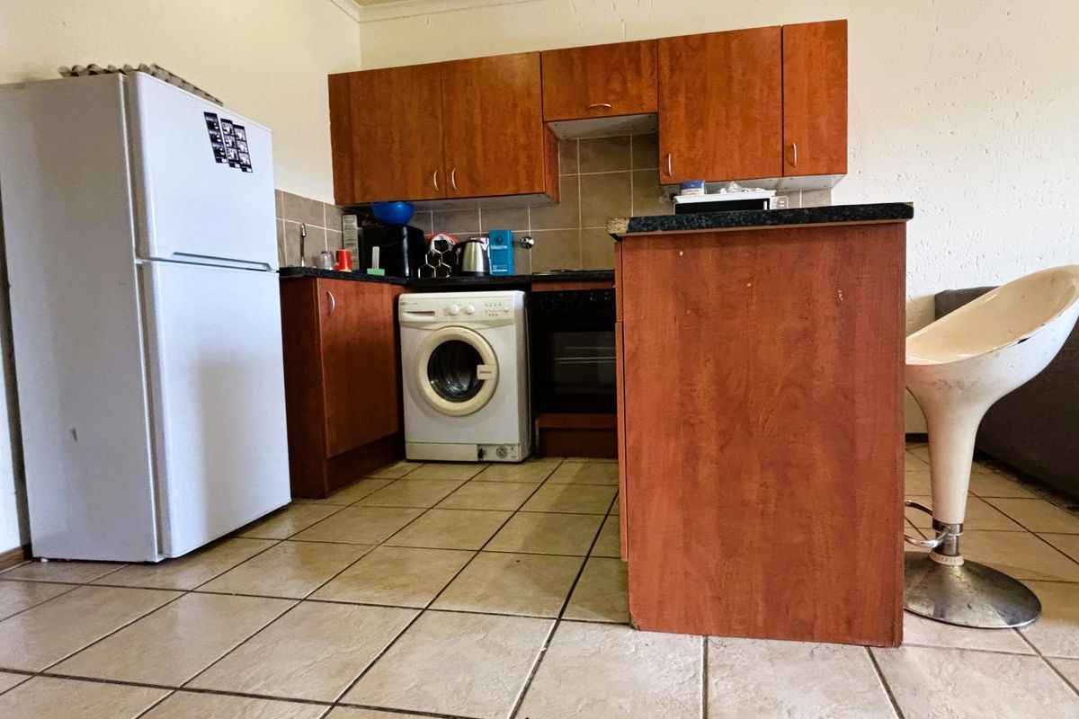 Compact kitchen featuring wood-look laminate cabinetry, tiled backsplash, and built-in oven, offering a functional layout with tiled flooring throughout.
