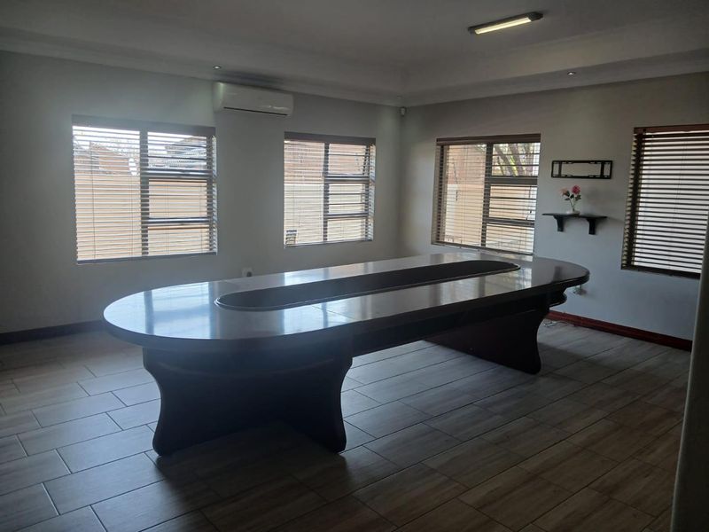 A professional office space featuring tiled flooring, recessed lighting, and multiple windows with venetian blinds, providing a bright and functional work environment.
