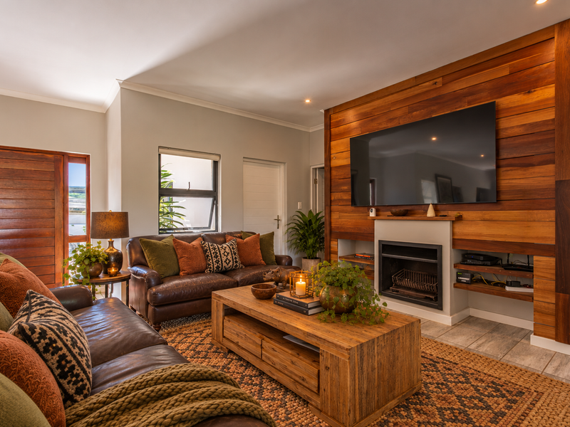 A cozy living room featuring a prominent wood-paneled feature wall with a built-in fireplace and tiled flooring.