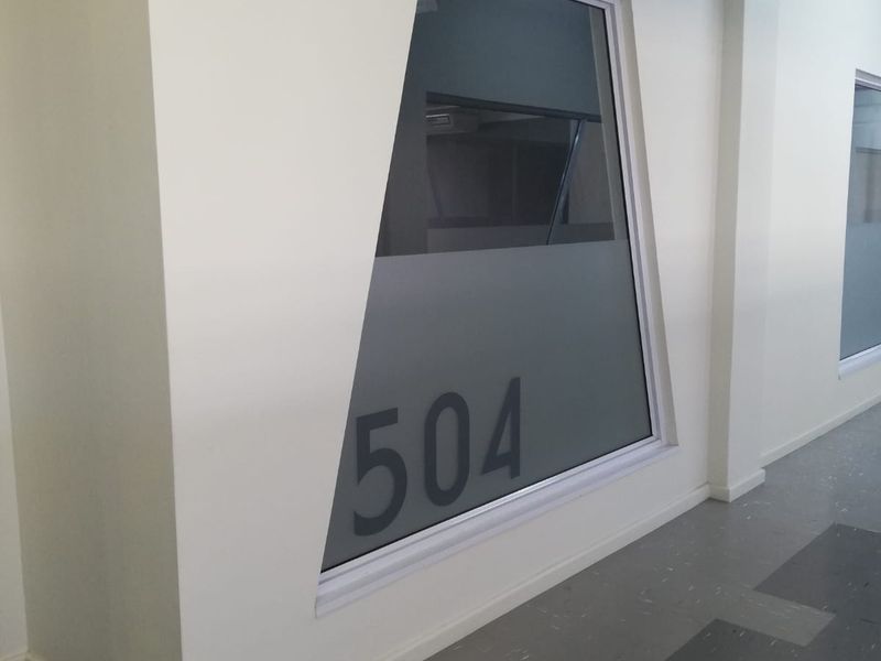A clean, modern office hallway featuring vinyl flooring and a uniquely shaped frosted glass window with suite number 504.