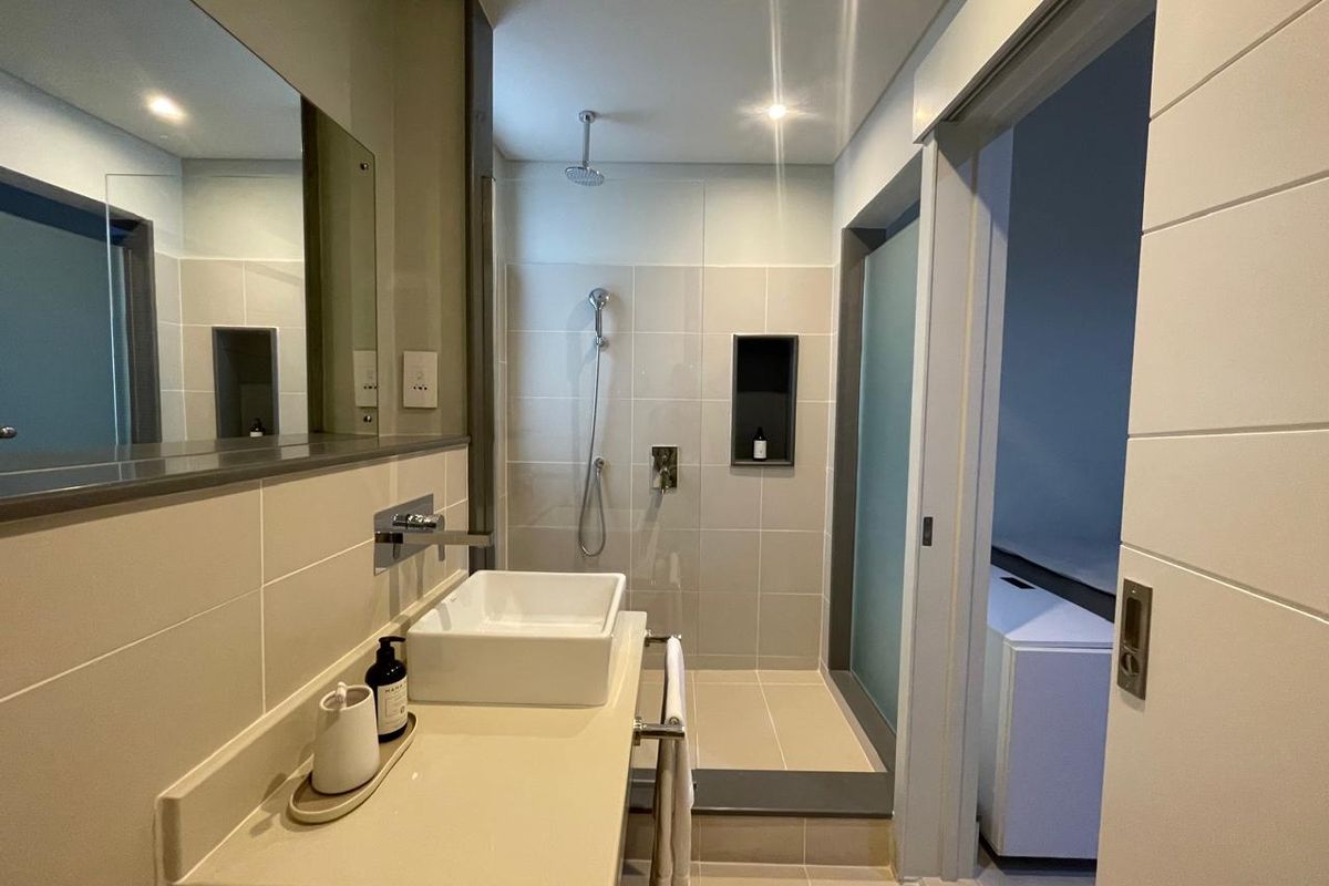 Modern bathroom featuring a vessel sink, wall-mounted faucet, walk-in shower with a built-in niche, and large vanity mirror.