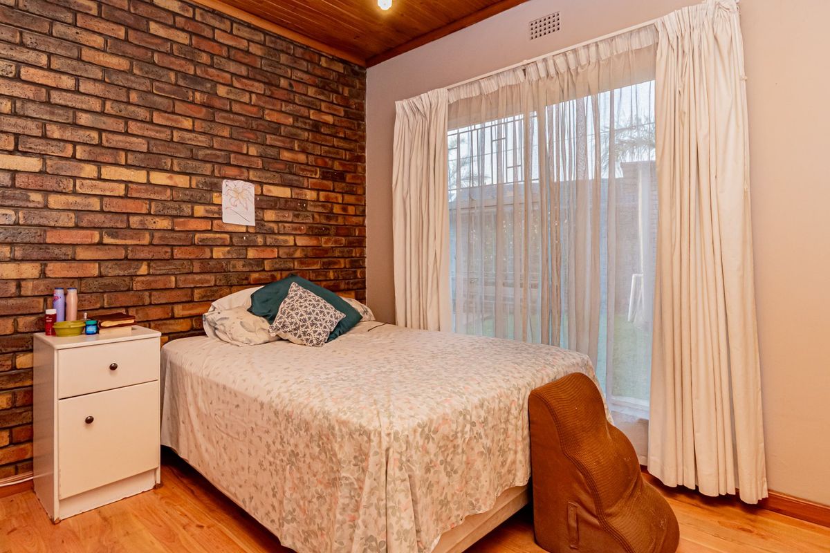 Bedroom featuring an exposed brick wall, timber ceiling, and sliding glass door providing access to the garden.