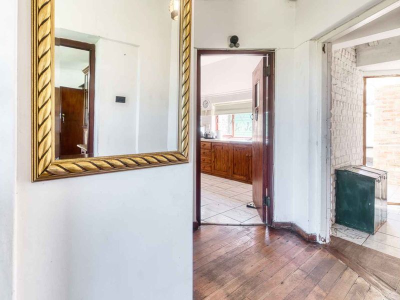 A transitional hallway featuring timber flooring and exposed brickwork, providing access to adjacent living and utility areas.
