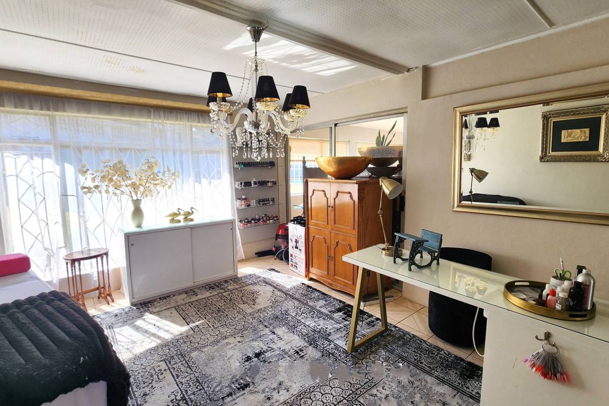 A multi-purpose room featuring tiled flooring, a crystal chandelier, and sliding glass doors, currently utilized as a workspace.