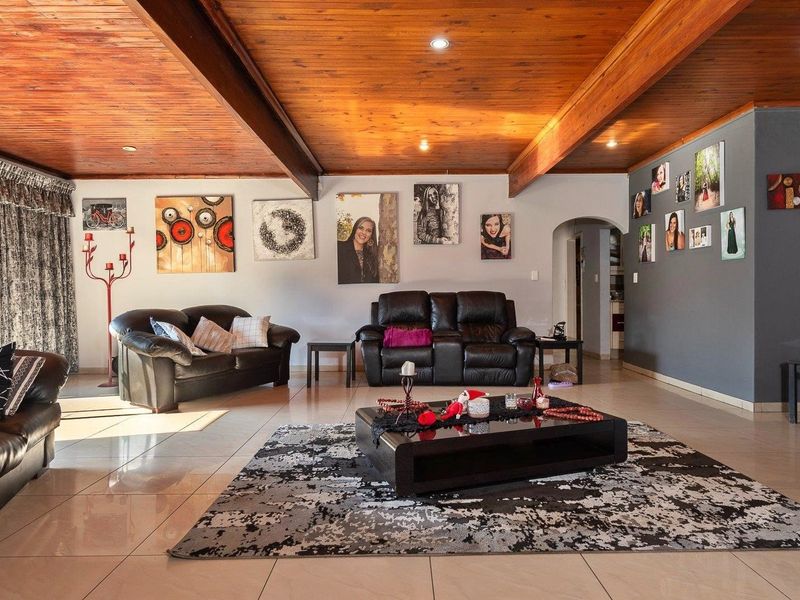 Spacious living room featuring a warm timber-clad ceiling with exposed beams, recessed lighting, and neutral tiled flooring, creating a comfortable and inviting atmosphere.
