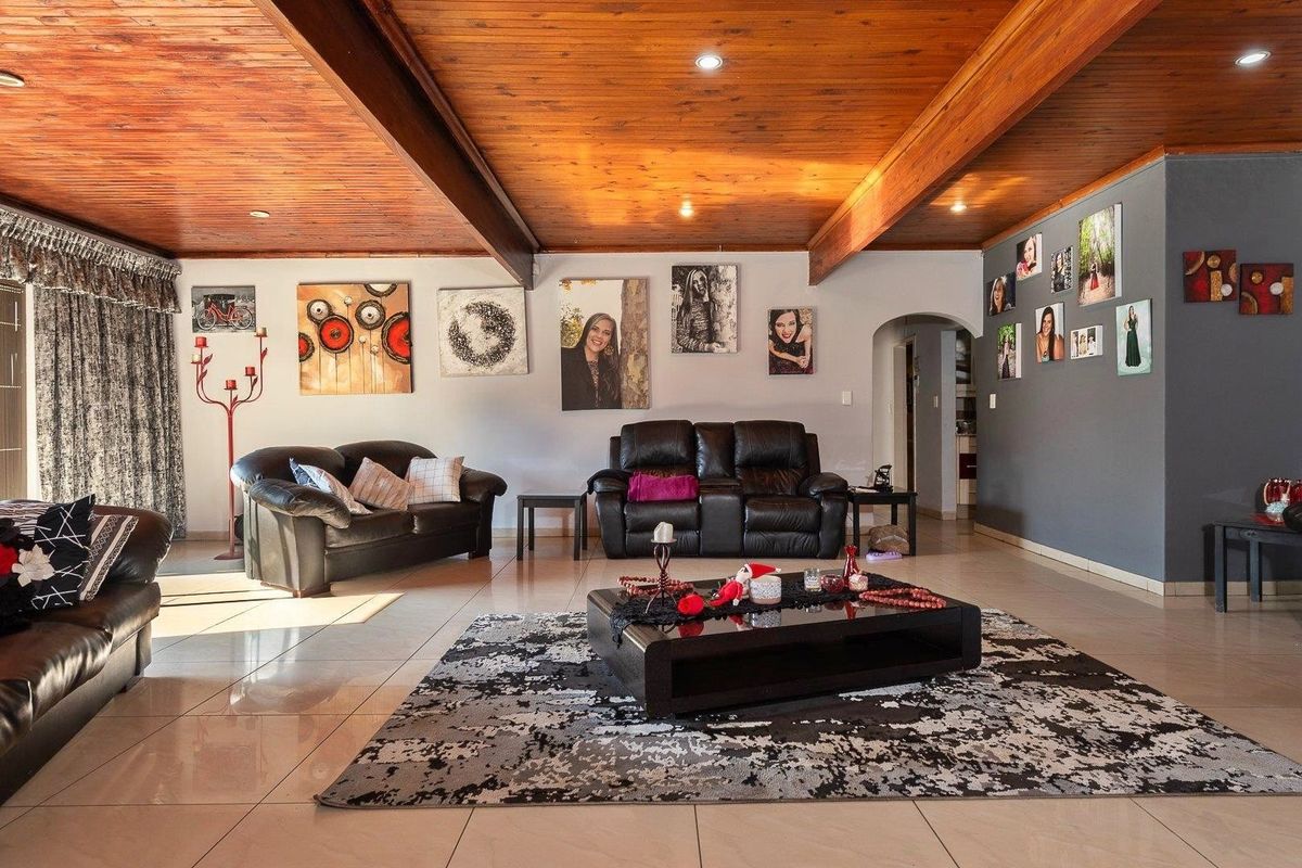 Spacious living room featuring a warm timber-clad ceiling with exposed beams, recessed lighting, and neutral tiled flooring, creating a comfortable and inviting atmosphere.