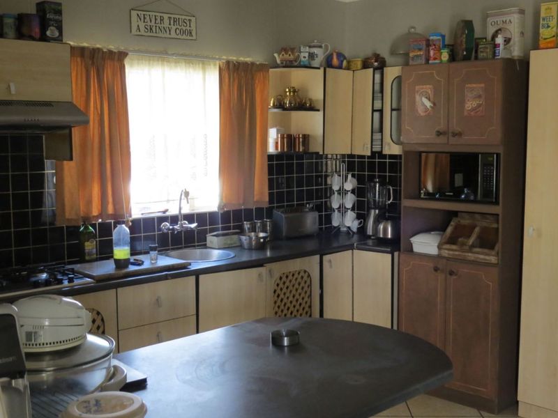 A functional kitchen featuring built-in cabinetry, a gas hob with extractor fan, integrated oven housing, and a stainless steel sink.