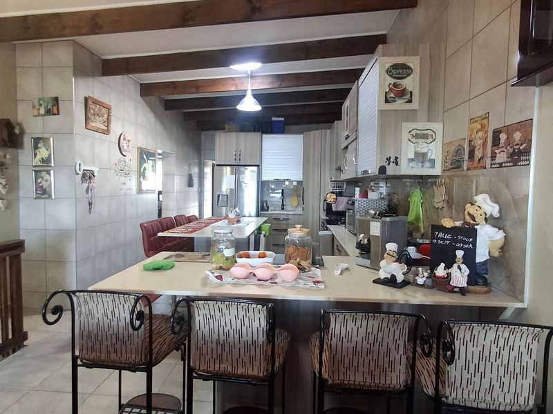 Open-plan kitchen featuring exposed timber ceiling beams, tiled wall finishes, and a functional breakfast bar counter with integrated cabinetry.