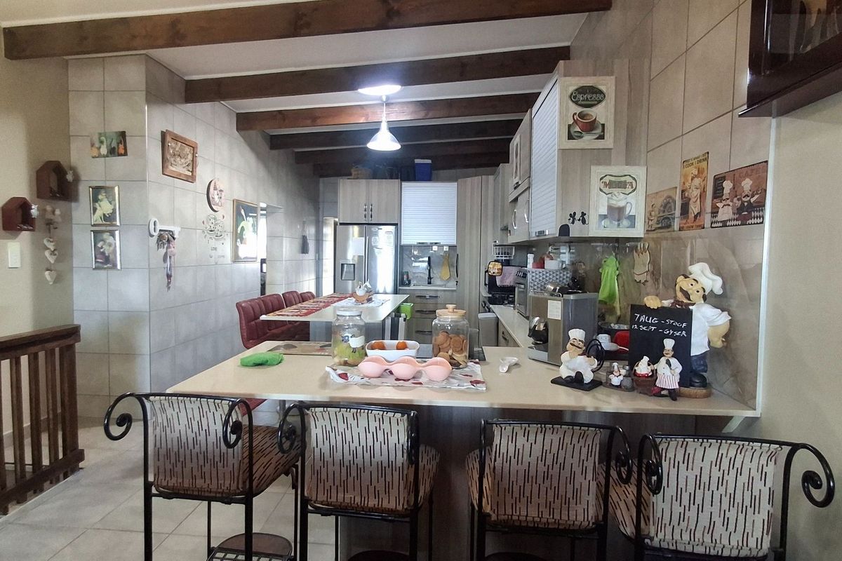 Open-plan kitchen featuring exposed timber ceiling beams, tiled wall finishes, and a functional breakfast bar counter with integrated cabinetry.