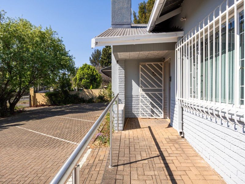 Front entrance area featuring brick paving, a secure metal gate, and protective security bars on the windows.