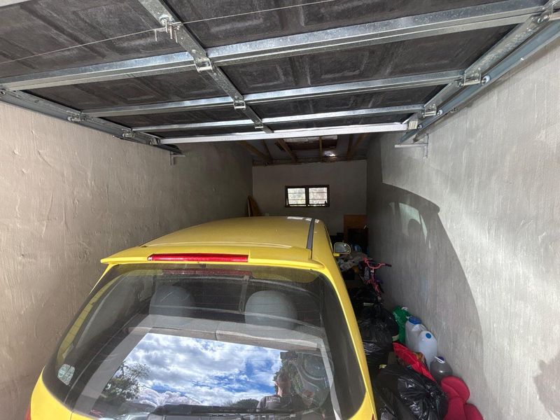 A single-car garage featuring a sectional overhead door, exposed roof rafters, and unfinished wall surfaces.