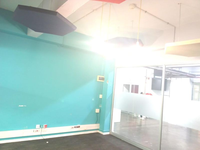 Empty office space featuring acoustic ceiling panels, a glass partition wall, and exposed industrial-style ceiling elements.