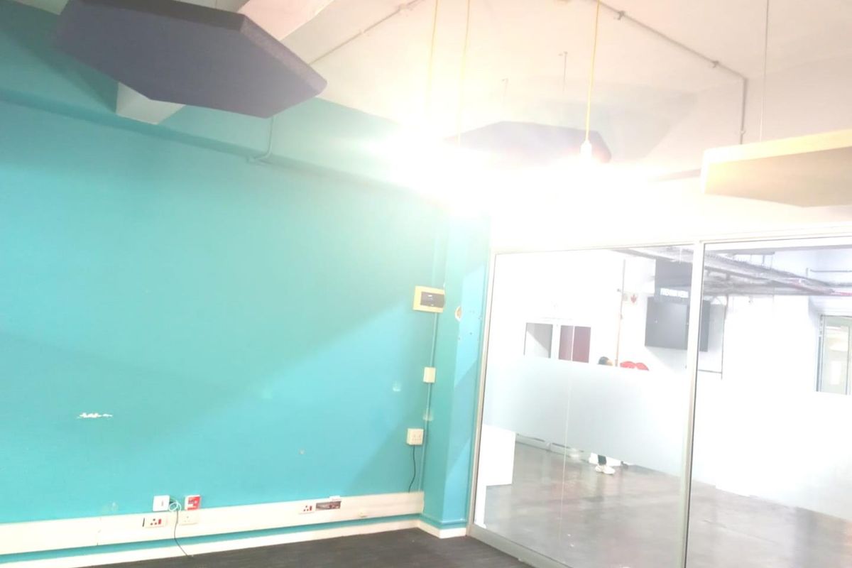 Empty office space featuring acoustic ceiling panels, a glass partition wall, and exposed industrial-style ceiling elements.