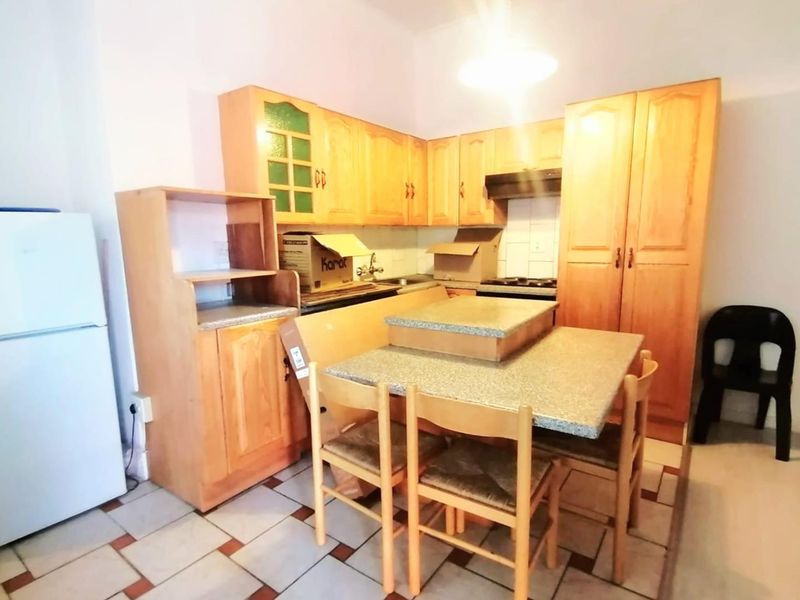 A dated kitchen featuring wooden cabinetry, laminate countertops, and tiled flooring, offering potential for a modern renovation to enhance functionality and aesthetic appeal.